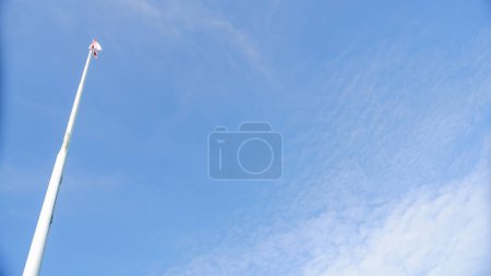 Ein weißer Fahnenmast vor strahlend blauem Himmel, Foto von unten