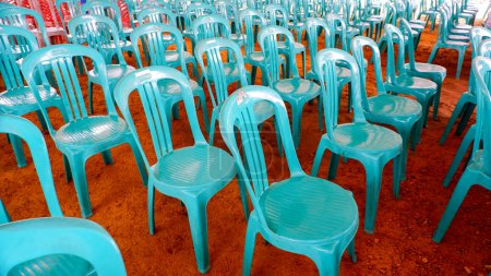Les chaises en plastique sont disposées en rangées et soigneusement sur la surface brunâtre du sol