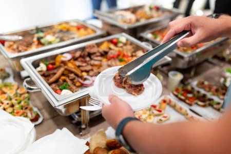 Man serving himself with barbecue meat and at buffet table