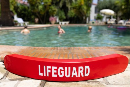 Lifeguard rescue tube at the edge of swimming pool.