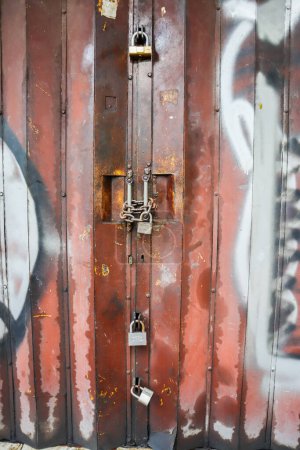 Foto de Vieja puerta plegable cerrada con candado y cadena. surabaya, indonesia - 6 maret 2024 - Imagen libre de derechos