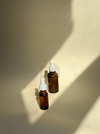 Foto de Dos botellas de suero sobre fondo desnudo con luz solar. Una rutina de belleza. Cuidado de la piel - Imagen libre de derechos