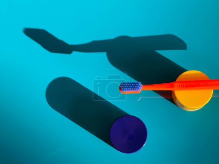 Foto de Cepillo de dientes de color naranja sobre un fondo azul con objetos brillantes. Bodegón. - Imagen libre de derechos