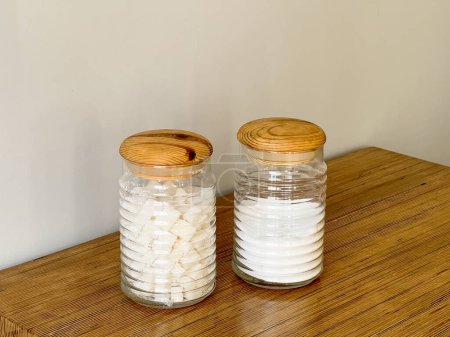 Foto de Dos frascos de vidrio llenos de azúcar sobre un fondo gris. Utensilios de cocina. - Imagen libre de derechos