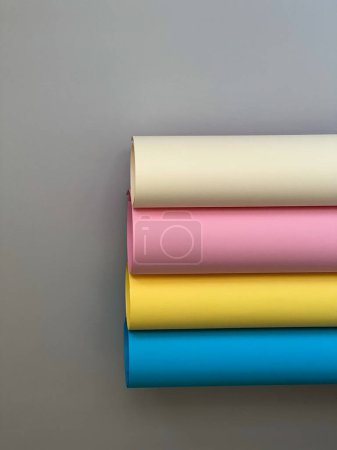 Foto de 4 rollos de papel de colores sobre un fondo gris simple. Amarillo, azul, beige, rosa - Imagen libre de derechos