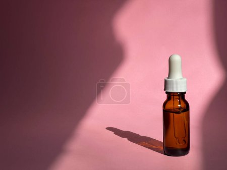 Foto de Frasco cosmético transparente con suero sobre fondo rosa con luz solar. Una rutina de belleza. Cáscara - Imagen libre de derechos
