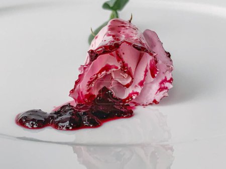 Foto de Una sola flor en el plato blanco. Pétalos en mermelada. Reflexión - Imagen libre de derechos