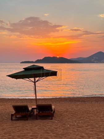 Foto de Dos lujosas tumbonas con vistas a la bahía y la puesta de sol en las montañas. Un lugar ideal para relajarse alma, espacio libre para el texto - Imagen libre de derechos