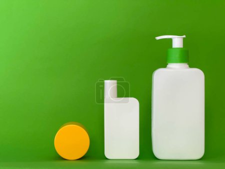 Foto de Conjunto de tres frascos cosméticos sobre un fondo verde brillante. Botellas de productos para el cuidado de la piel con espacio vacío para marca - Imagen libre de derechos