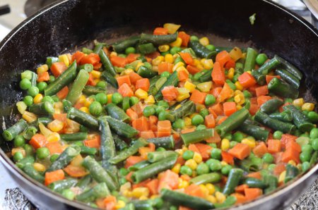 Bright vegetable mix in a frying pan.Frying vegetables in a frying pan.Healthy frozen vegetables. Cooking.Vegetarian food.Assorted vegetables.Mexican mix of vegetables for frying.Table setting.salad.assorted vegetables.