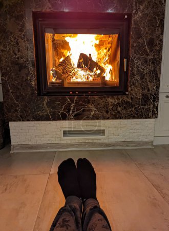 Photo for Sitting on a fireplace in a warm cozy winter home.warming up near the fireplace.home hearth.cold.heating the apartment and house with a wood fireplace.cozy warm atmosphere in the house.beautiful flames in the fireplace.real fireplace.warmth in house - Royalty Free Image
