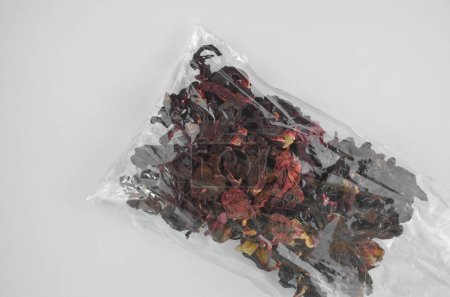 Foto de Hibisco egipcio té rojo seco (karkade) en una bolsa de plástico transparente, primer plano (macro), vista superior - Imagen libre de derechos