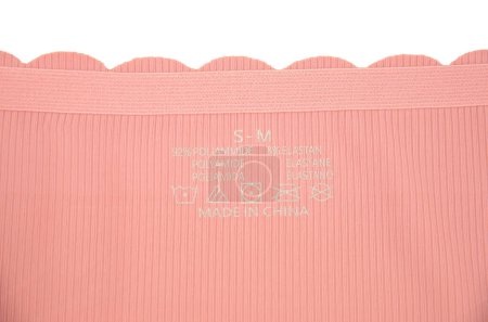 Peach rosa sin costuras (invisible) ropa interior de mujer (lencería, bragas, calzoncillos) con borde ondulado aislado primer plano con una etiqueta impresa en el interior