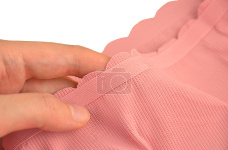 Pfirsichrosa nahtlose (unsichtbare) Damenunterwäsche (Dessous, Höschen, Slip) mit gewelltem Rand isoliert, Gummiband Nahaufnahme in der Hand