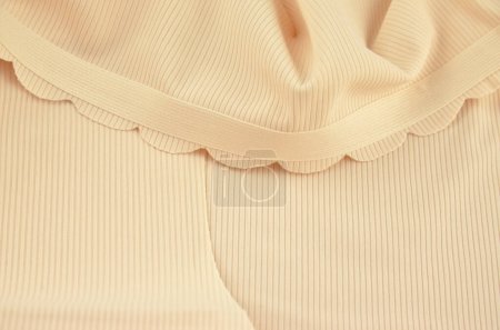 Ropa interior femenina sin costuras (invisible) beige (lencería, bragas, calzoncillos) con borde ondulado aislado, primer plano de goma