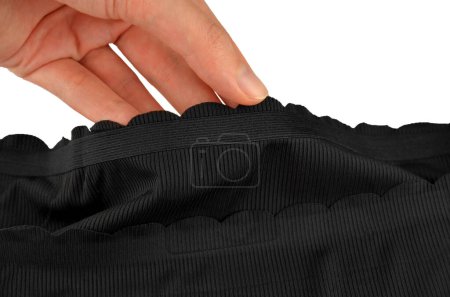 Black seamless (invisible) women's underwear (lingerie, panties, briefs) with wavy edge isolated, rubber band closeup in a hand