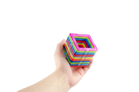 A group of colorful transparent magnet squares (puzzle game for kids) connected into a tunnel in a hand on a white background