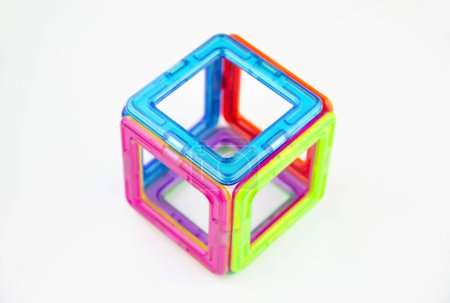 Un cubo hecho de cuadrados de imán transparente de colores (constructor de rompecabezas para niños), primer plano aislado sobre un fondo blanco