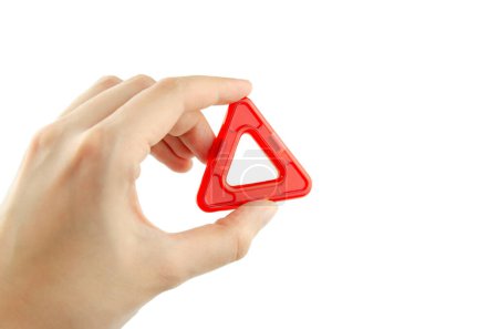 Foto de Triángulo plástico rojo del kit constructor de imanes transparentes (constructor de rompecabezas para niños) en una mano aislada sobre un fondo blanco - Imagen libre de derechos