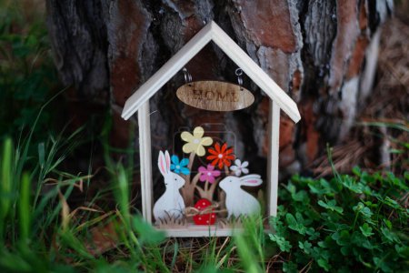 Foto de Casa de madera de Pascua con conejos entre hierba y madera sobre fondo. Concepto Pascua - Imagen libre de derechos