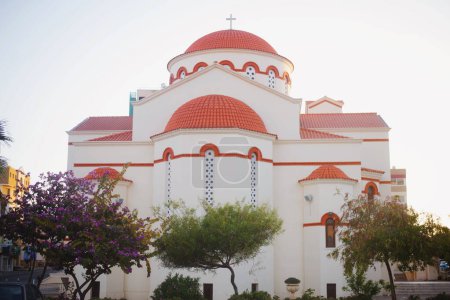 Téléchargez les photos : Belle vue sur l'église orthodoxe Saint Nikolaos et les arbres en fleurs au coucher du soleil. Limassol, Chypre - en image libre de droit