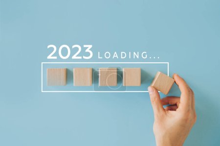 Main féminine mettant cube en bois pour le compte à rebours jusqu'en 2022. Année de chargement de 2022 à 2023. Nouveau concept de début d'année