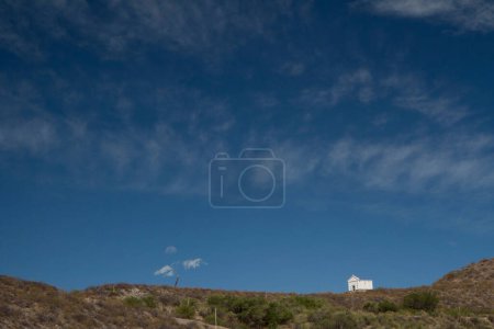 Téléchargez les photos : Vue allégorique d'une petite chapelle au sommet d'une montagne sous un beau ciel bleu profond avec des nuages dramatiques. - en image libre de droit