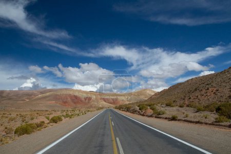 Roadtrip in die Wildnis. Fahrt entlang der Wüste Asphaltstraße durch die trockene Wüste und bunte Berge unter einem schönen blauen Himmel.  