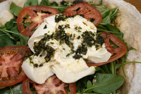 Photo for Italian pizza. Closeup view of a pizza with burrata cheese, pesto, tomatoes and arugula. - Royalty Free Image