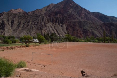 Téléchargez les photos : L'amour du sport. Vue panoramique d'un terrain de football vide dans le désert. Les buts rustiques du football, le sable et les montagnes environnantes par une chaude journée à Purmamarca, Jujuy, Argentine. - en image libre de droit