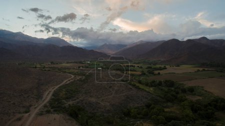 Foto de Paisaje rural. Hermosa puesta de sol en las montañas. Las colinas, valle, viñedos y campos de plantación al anochecer. - Imagen libre de derechos
