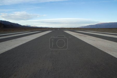 Téléchargez les photos : Transport. Large route droite de l'aérodrome d'asphalte à travers le désert et dans les montagnes. - en image libre de droit