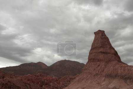 Photo for Geology. View of the sandstone and red rocky formation and mountains in the arid desert under a cloudy sky. - Royalty Free Image