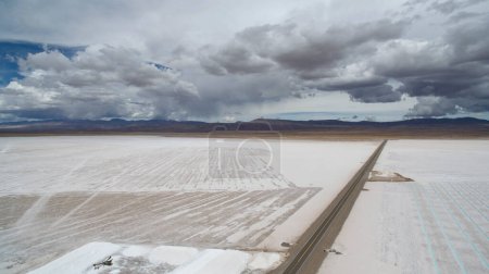 Photo for Salt industry. Aerial view of the natural salt flat and highway across the mines and salt pools, into the desert mountains. - Royalty Free Image
