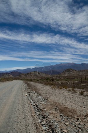 Photo for Desert route across the death valley. View of the dirt road, desert and mountains under a beautiful blue sky with clouds. - Royalty Free Image