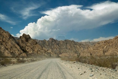 Photo for Dirt road across the desert. Driving through the rural highway in the death valley and rocky mountains. - Royalty Free Image