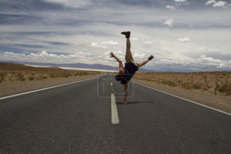 Foto de Breakdance. Recreativo. Joven caucásico hombre handstand y twirl en el asfalto desierto camino. - Imagen libre de derechos