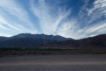 Téléchargez les photos : Beau lever de soleil dans les montagnes. Vue panoramique sur le chemin de terre le long du désert et de la chaîne de montagnes des Andes avec de belles couleurs de l'aube sous un ciel bleu profond avec des nuages. - en image libre de droit