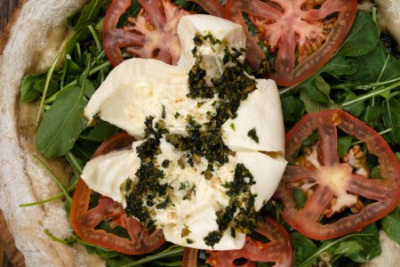 Photo for Italian pizza. Closeup view of a pizza with burrata cheese, pesto, tomatoes and arugula. - Royalty Free Image