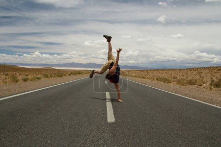 Photo for Breakdance. Recreational. Young caucasian man handstand and twirl in the asphalt desert road. - Royalty Free Image