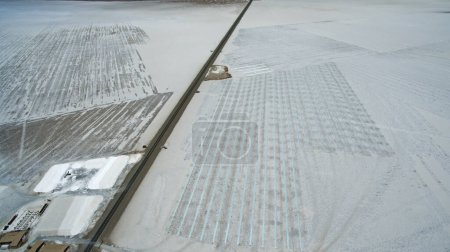 Téléchargez les photos : Sel naturel plat. Industrie. Vue aérienne de la route asphaltée traversant les mines de sel et les lacs salés artificiels. - en image libre de droit