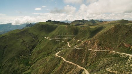 Aerial view of the dirt road in the green mountains. The curved road across Cuesta del Obispo hill in Salta, Argentina. 