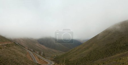 Photo for Dramatic landscape. Aerial view of the asphalt highway high in the mountains. The valley and hills under a cloudy sky. - Royalty Free Image