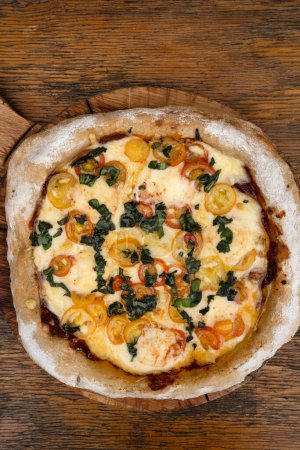 Téléchargez les photos : Vue rapprochée d'une pizza avec mozzarella et provolone, ail et tomates cerises. - en image libre de droit