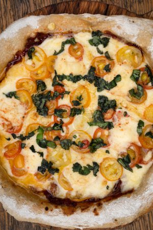 Foto de Vista de cerca de una pizza con queso mozzarella y provolone, ajo y tomates cherry. - Imagen libre de derechos