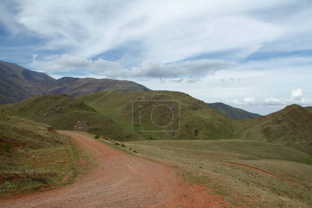 Foto de El camino de tierra a través del campo verde. Vista de la ruta del campo a través del valle y las montañas. - Imagen libre de derechos