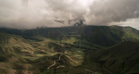 Foto de Vista aérea del camino de tierra a lo largo de la colina verde en un día nublado. - Imagen libre de derechos