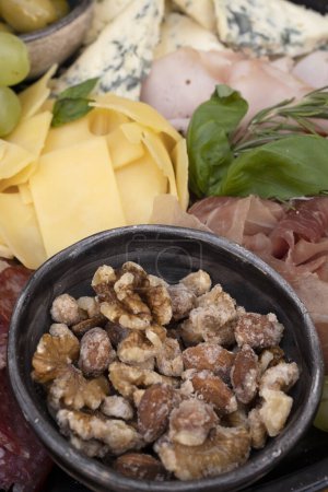 Photo for Food on the restaurant table. Close-up view of different dishes on wooden background. Meal with sliced salami, cheese, blue cheese, focaccia bread, italian boconccinos, walnuts, ham, cured ham and green olives on the wooden table. - Royalty Free Image