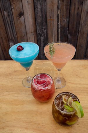 Téléchargez les photos : Des cocktails. Vue rapprochée de quatre boissons tropicales avec un fond en bois. - en image libre de droit