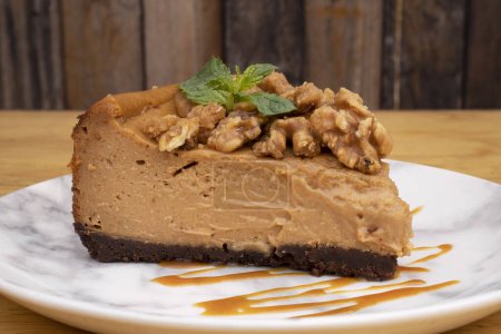 Photo for Sweet desserts. Close-up view of a slice of dulce de leche cheesecake with walnuts and caramel sauce. - Royalty Free Image